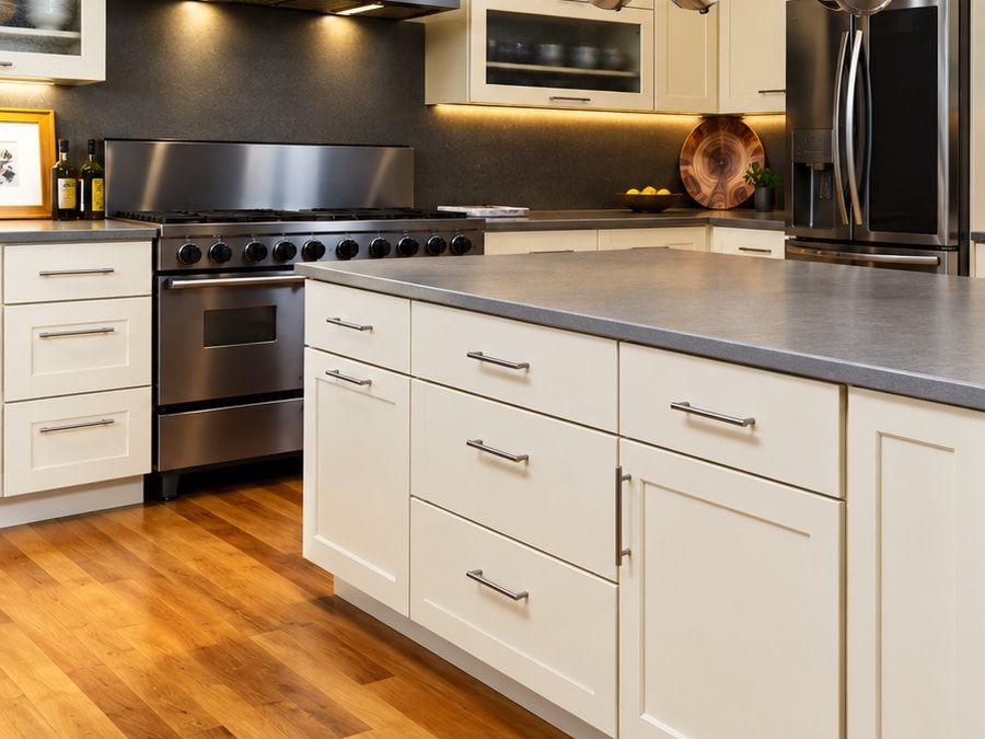 Kitchen island with cream cabinets, drawers with metal pulls, and a gray countertop.