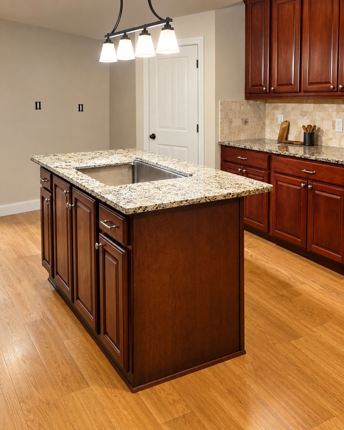 Kitchen island with dark wood cabinets, a light granite countertop, and an undermount sink.